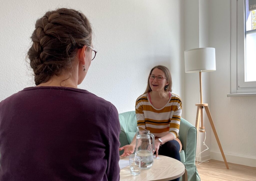 Zwei Frauen sitzen sich gegenüber und sprechen miteinander.