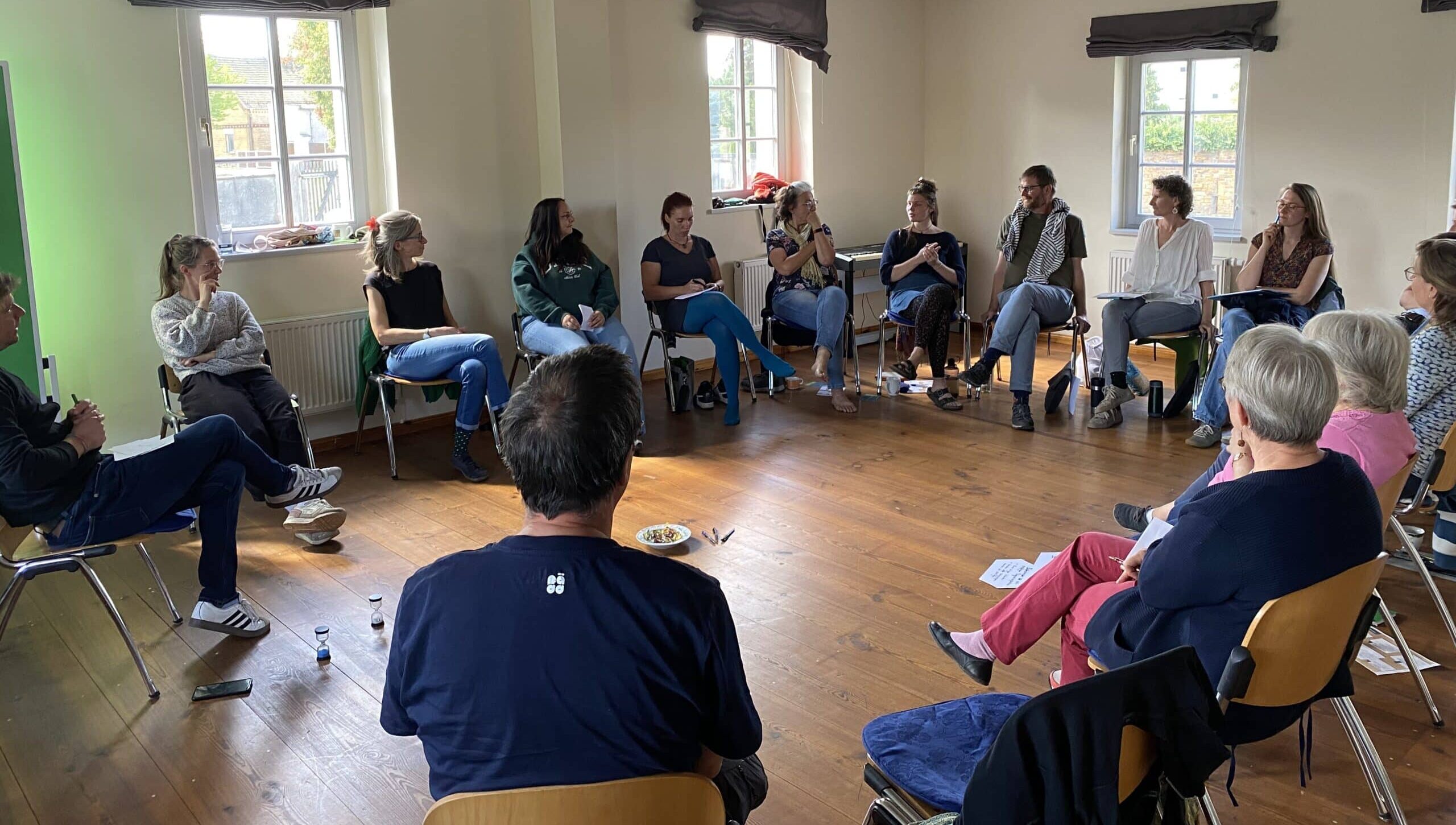 Mehrere erwachsene Personen sitzen in einem Stuhlkreis